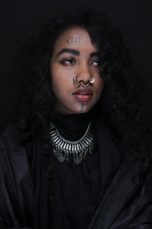 Foto di una donna con capelli neri e vestiti neri con piercing al naso